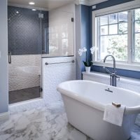 Elegant bathroom featuring a white freestanding bathtub and glass-enclosed walk-in shower with styli.