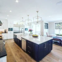 Luxury kitchen remodel featuring navy blue island with white quartz countertop, brass pendant lights, and white cabinetry by i BUILD KC